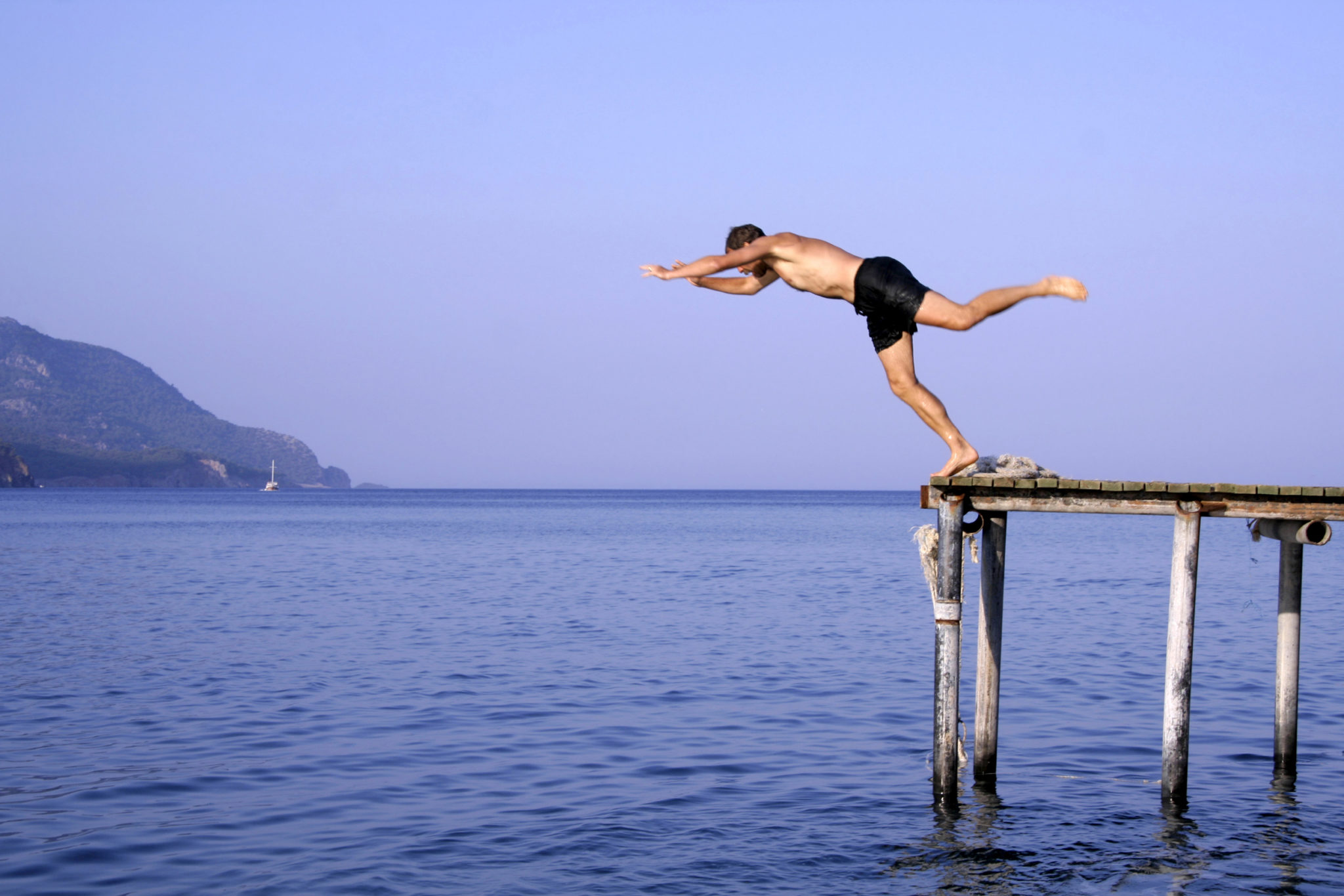 man jump diving from pier into sea